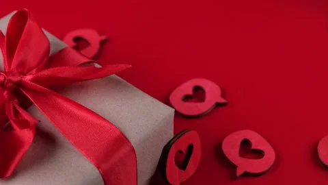 Composition with a gift box tied with a red ribbon with a bow, hearts close-up Stock Footage 167900101