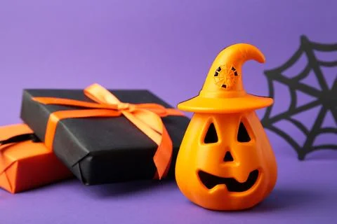 Composition with gift boxes and pumpkin for Halloween on violet background Stock Photos
