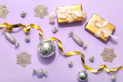 Composition with gift boxes, disco balls and Christmas decor on lilac backgro Stock Photos