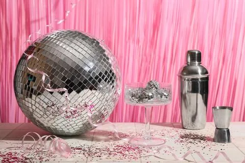 Composition with glass, bartender tools and disco balls on white tile table n Stock Photos