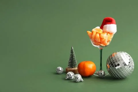 Composition with glass, disco balls, tangerines and Christmas decor on green  Stock Photos