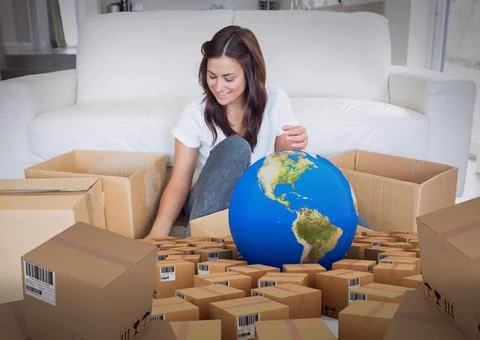 Composition of globe and cardboard boxes with woman unpacking in new home Stock Photos