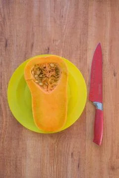 Composition - half-cut pumpkin lying on a plate of yellow with a red knife Stock Photos