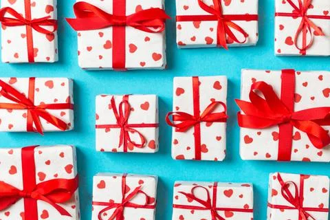 Composition of holiday white gift boxes with red hearts on colorful backgroun Stock Photos