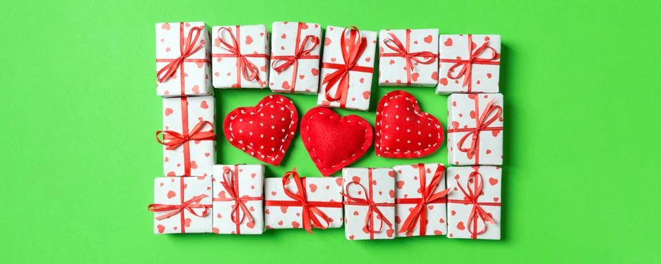 Composition of holiday white gift boxes and red textile hearts on colorful .. Stock Photos