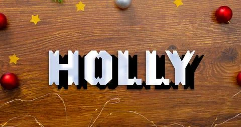 Composition of holly text over christmas decorations on table Stock Illustration