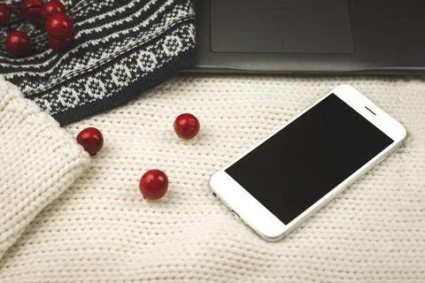 Composition with knitted background, sweaters, decoration and black smartphon Stock Photos