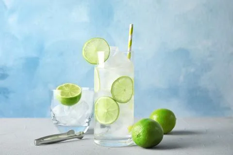 Composition with lime drink and ice cubes in glass on table against color bac Stock Photos