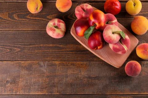 A composition from many varieties of peach on a cutting board on a brown wood Stock Photos