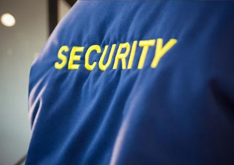 Composition of midsection of security guard blue jacket with yellow text over Stock Photos