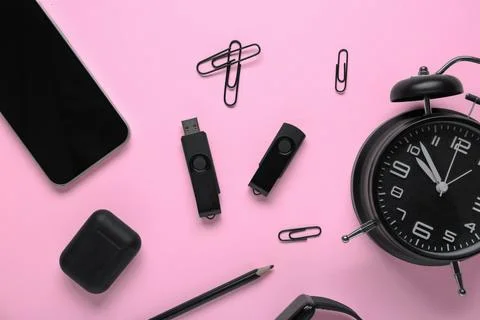 Composition with mobile phone, alarm clock and modern flash drive on pink bac Stock Photos