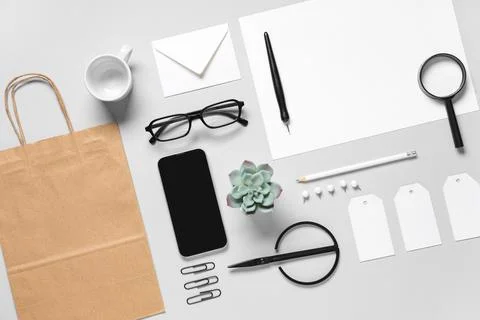 Composition with mobile phone, scissors and delivery paper bag on grey backgr Stock Photos