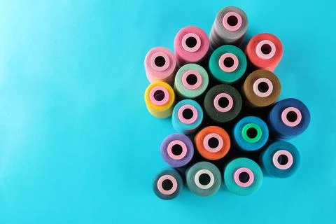 Composition with multi-colored thread spools on a bright blue background with Stock Photos