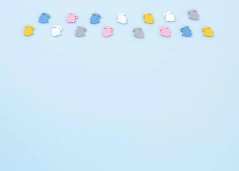 Composition of multi-colored wooden small rabbits on a blue background. Easte Stock Photos