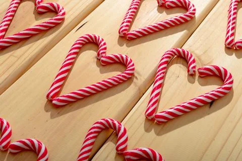 Composition of multiple candy canes in shape of heart on wooden background Foto stock