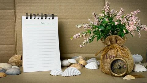 Composition with a notebook, pen, flower, and compass against a background of pa Stock Photos