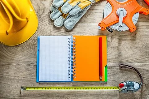 Composition of notebook pencil safety gloves tape measure hard hat on wooden Stock Photos