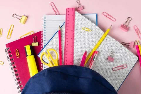 Composition of notebooks and school equipment in navy case on pale pink surface Stock Photos