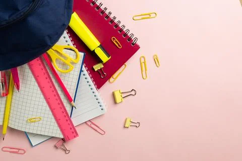 Composition of notebooks and school equipment in navy case on pale pink surface Stock Photos