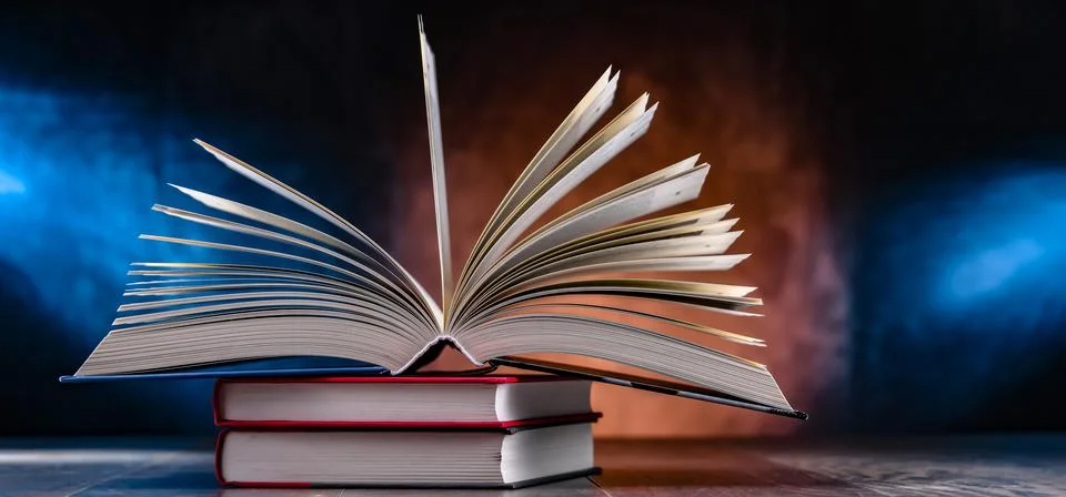 A composition with an open book lying on a stack of other books Foto stock