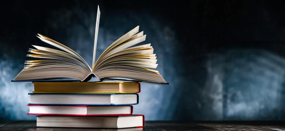 A composition with an open book lying on a stack of other books Stockfoto's