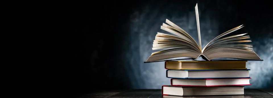 A composition with an open book lying on a stack of other books Stockfoto's