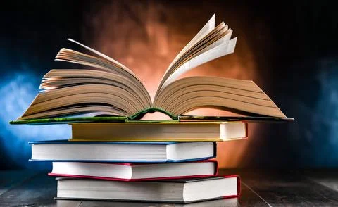 A composition with an open book lying on a stack of other books Stock Photos