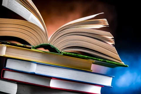 A composition with an open book lying on a stack of other books Stock Photos