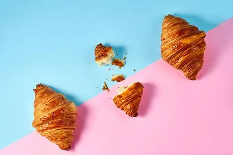 Composition-pattern with 3 croissants and one broken on a blue and pink backg Stock Photos