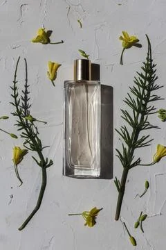 A composition of a perfume bottle surrounded by two green leaves and yellow Photos