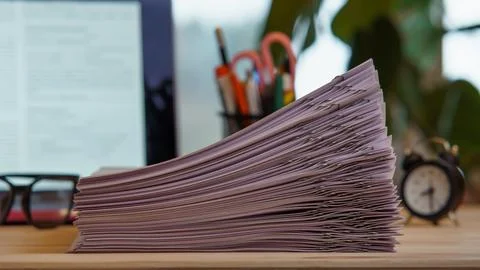 Composition of pile of papers sorted with paperclips, glasses, clock, offic.. Foto stock