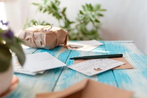 A composition of postcards, craft envelope, a pen with a letter and a parcel. Stock Photos