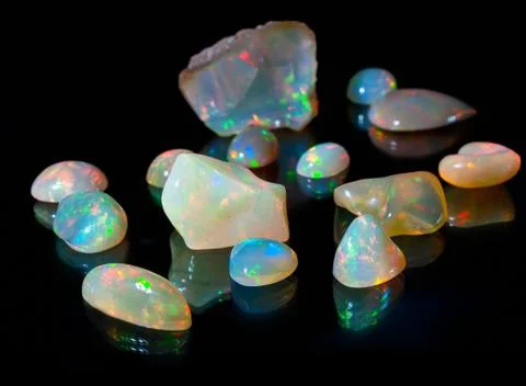 Composition of precious opal jewels. Cuts and rough material Stock Photos
