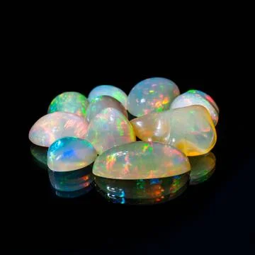 Composition of precious opal jewels. Cuts and rough material Stock Photos