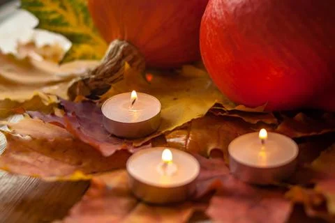 Composition with pumpkins and candles on maple leaves on wooden background. S Stock Photos