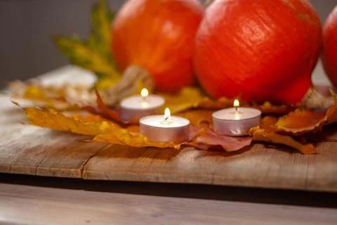 Composition with pumpkins and candles on maple leaves on wooden background. S Stock Photos