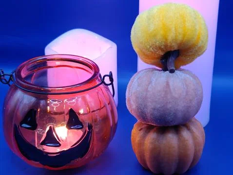 A composition of pumpkins and colored candles on a blue background, macro photog Stock Photos