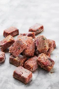 Composition with raw square cutlets on a light background. Natural dog food Stock Photos