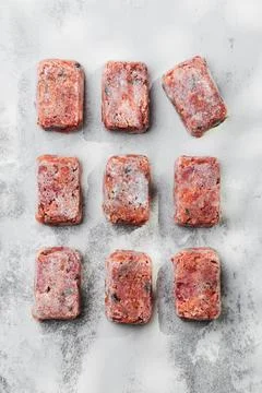 Composition with raw square cutlets on a light background. Natural dog food Stock Photos