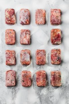 Composition with raw square cutlets on a light background. Natural dog food Stock Photos