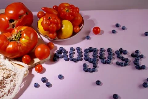 A composition of red and yellow large and small tomatoes on a plate and a w.. Foto stock