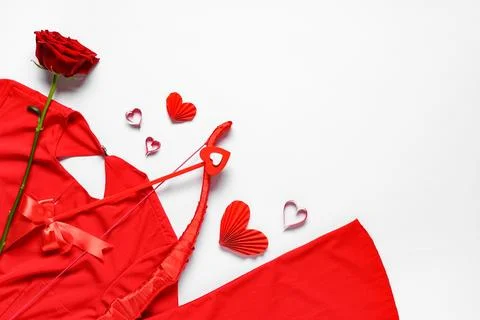 Composition with red dress, cupid's bow and rose flower on light background.  Stock Photos