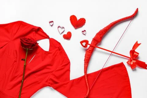 Composition with red dress, cupid's bow and rose flower on light background.  Stock Photos