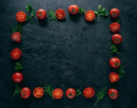 Composition of red tomatoes and green fresh parsley and dill lying on dark ba Foto stock