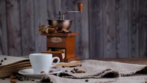 Composition of the retro coffee grinder, cup of coffee and old book Stock Footage 130254364