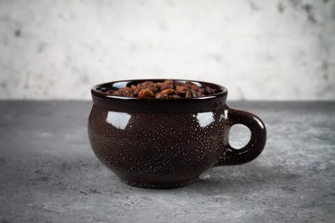 Composition of a round brown ceramic Cup with coffee beans on a gray concrete Фото
