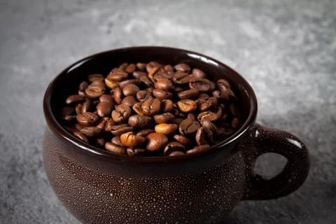 Composition of a round brown ceramic Cup with coffee beans on a gray concrete Foto stock