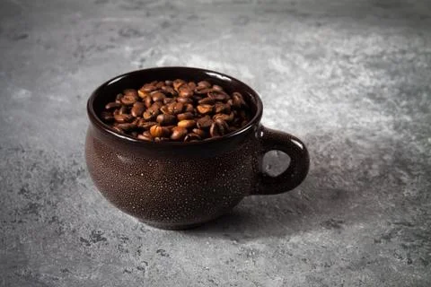 Composition of a round brown ceramic Cup with coffee beans on a gray concrete Foto stock
