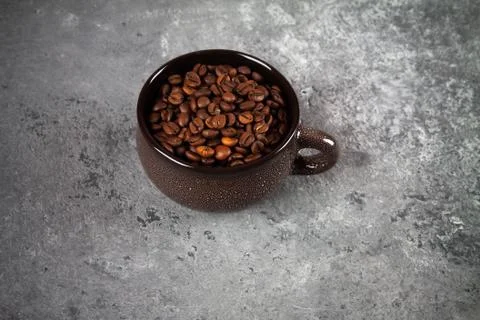 Composition of a round brown ceramic Cup with coffee beans on a gray concrete Stock-Fotos