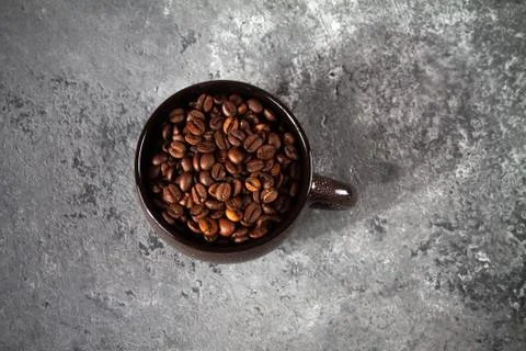 Composition of a round brown ceramic Cup with coffee beans on a gray concrete Stock Photos